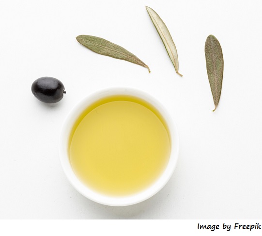 Composición de recipiente con aceite de oliva virgen, hojas de olivo y una aceituna negra