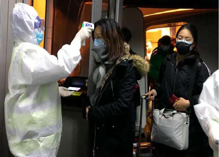 Personal sanitario con traje de protección CoCiD19 mide la temperatura a una viandante
