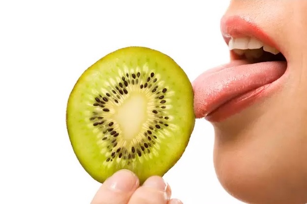 Mujer tocando kiwi con la lengua