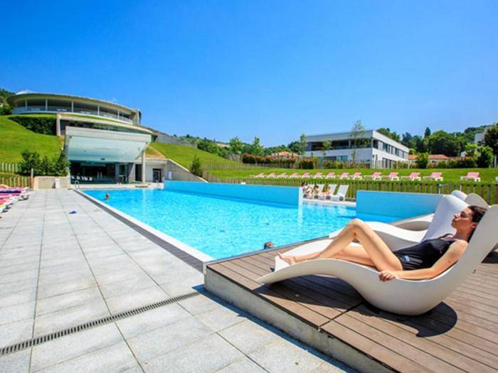 Mujer tumbada en hamaca tomando el sol en piscina de Las Caldas Villa Termal