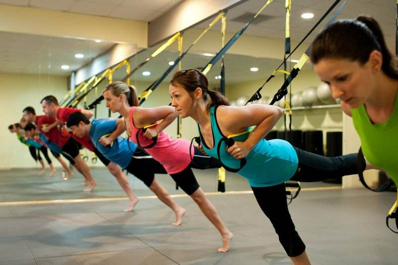 Mujeres realizando ejercicios de TRX en una clase