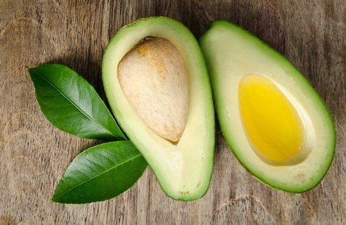 Aguacate partido en dos secciones longitudinales, una de ellas conteniendon aceire virgen