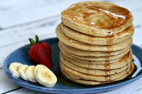 Pila de tortitas de avena con fresas y plátano dispuestas en un plato