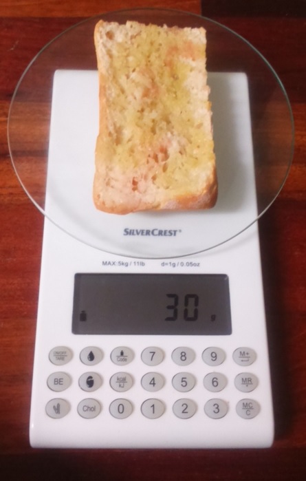 Fotografía a vista de pájaro de báscula digital con tapa inferior del pan untada de aceite.