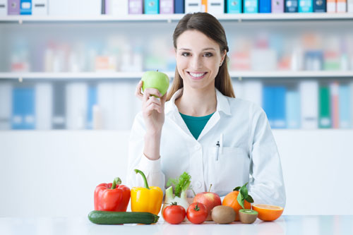 Dietista-nutricionista sujetando una manzana con la mano derecha