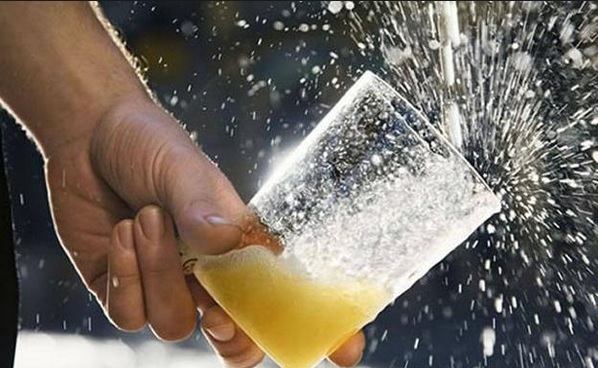 Mano sujetando un vaso de sidra mientras se vierte un culín de sidra