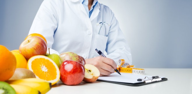 Dietista-Nutricionista escribiendo en hoja próxima a frutas variadas